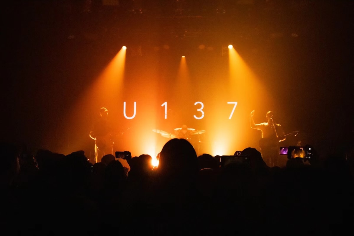 A band silhouetted by orange stage lights above a dark audience