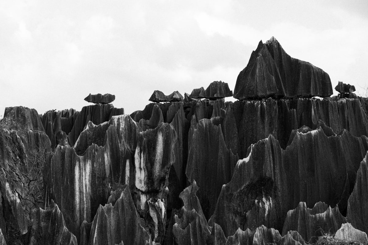Black-and-white view of steep eroded rock formations beneath a pale sky