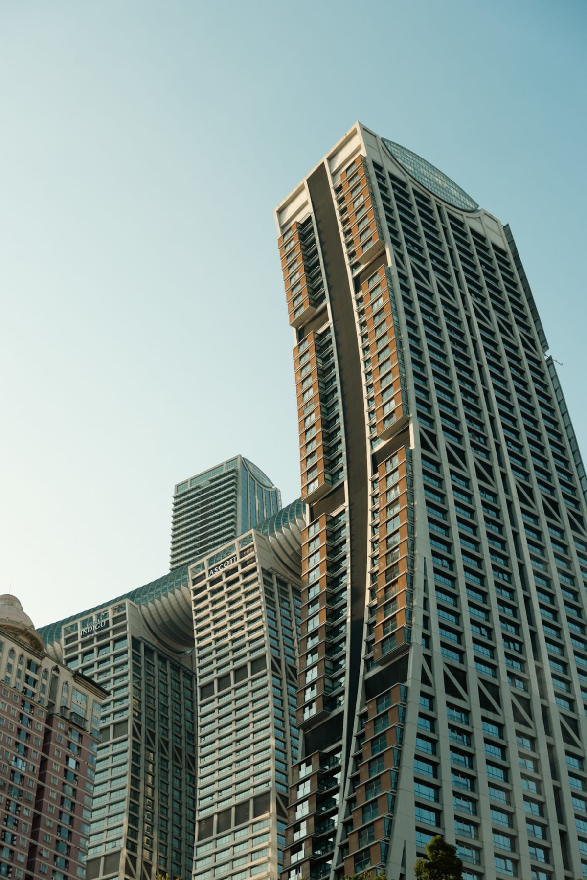Modern Chongqing towers photographed from below against a pale blue sky