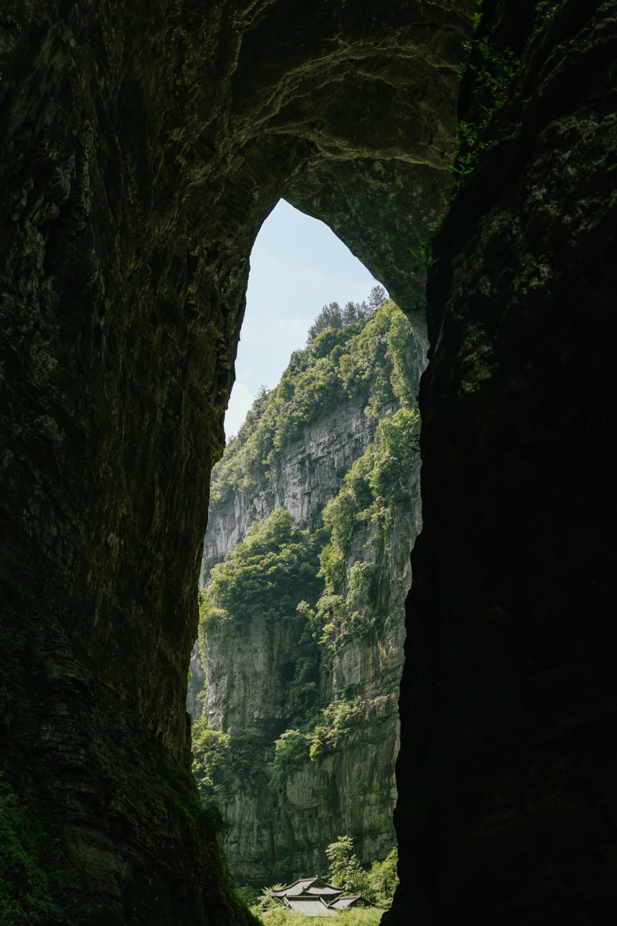 A sunlit cliff and traditional rooftops framed by a narrow rock opening