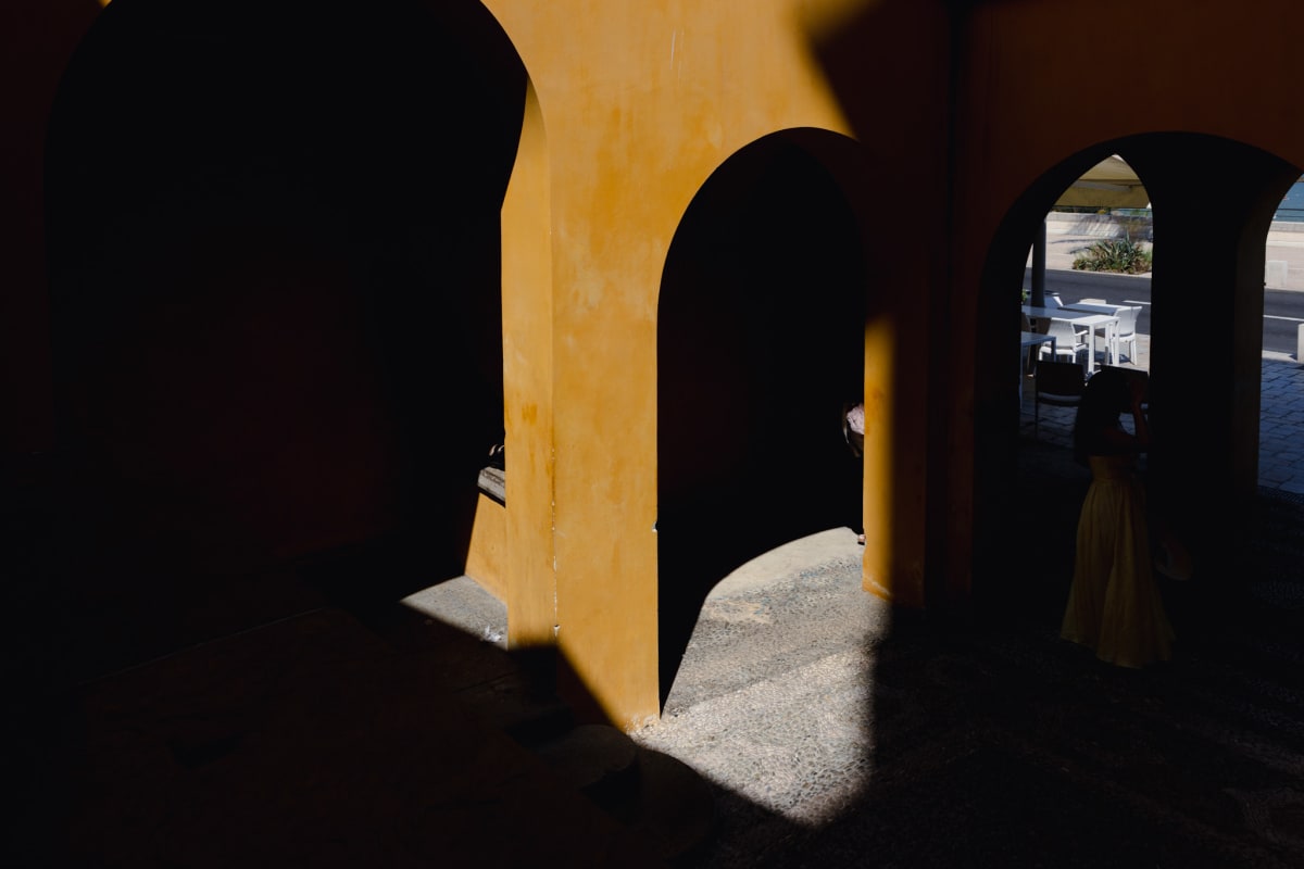 Deep shadows and sunlight forming geometric shapes beneath ochre arches