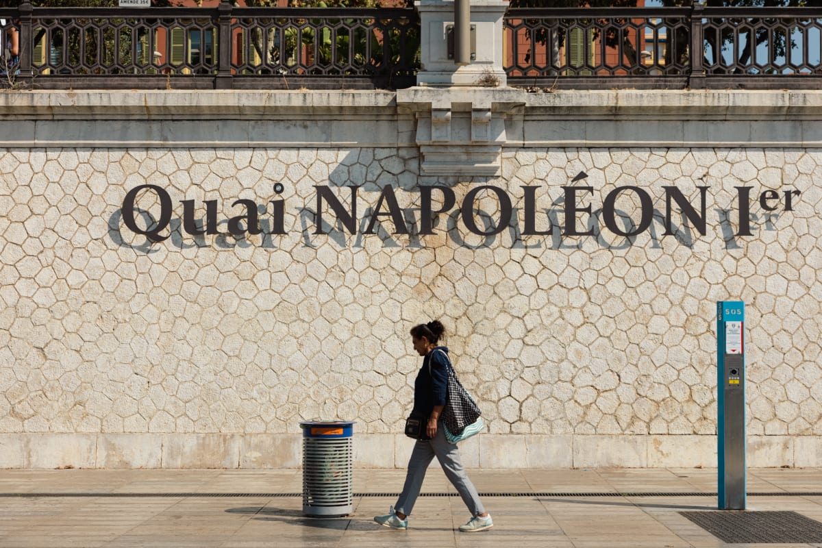 A pedestrian walking beneath the Quai Napoléon Premier sign