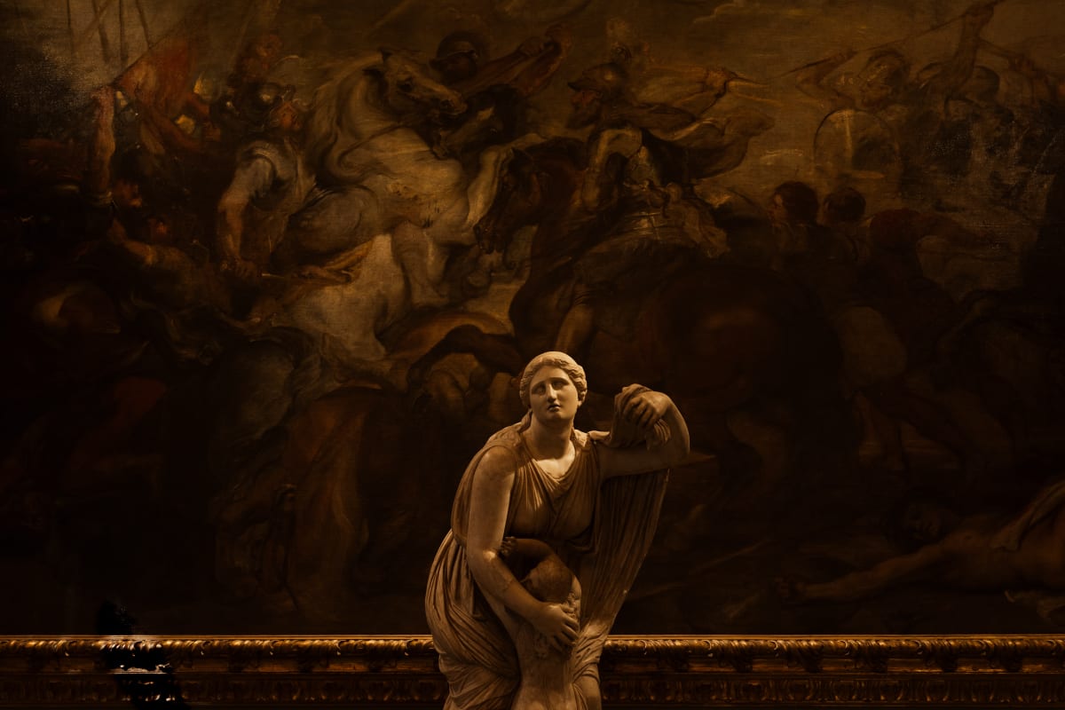 A classical female statue standing before a dark painted scene