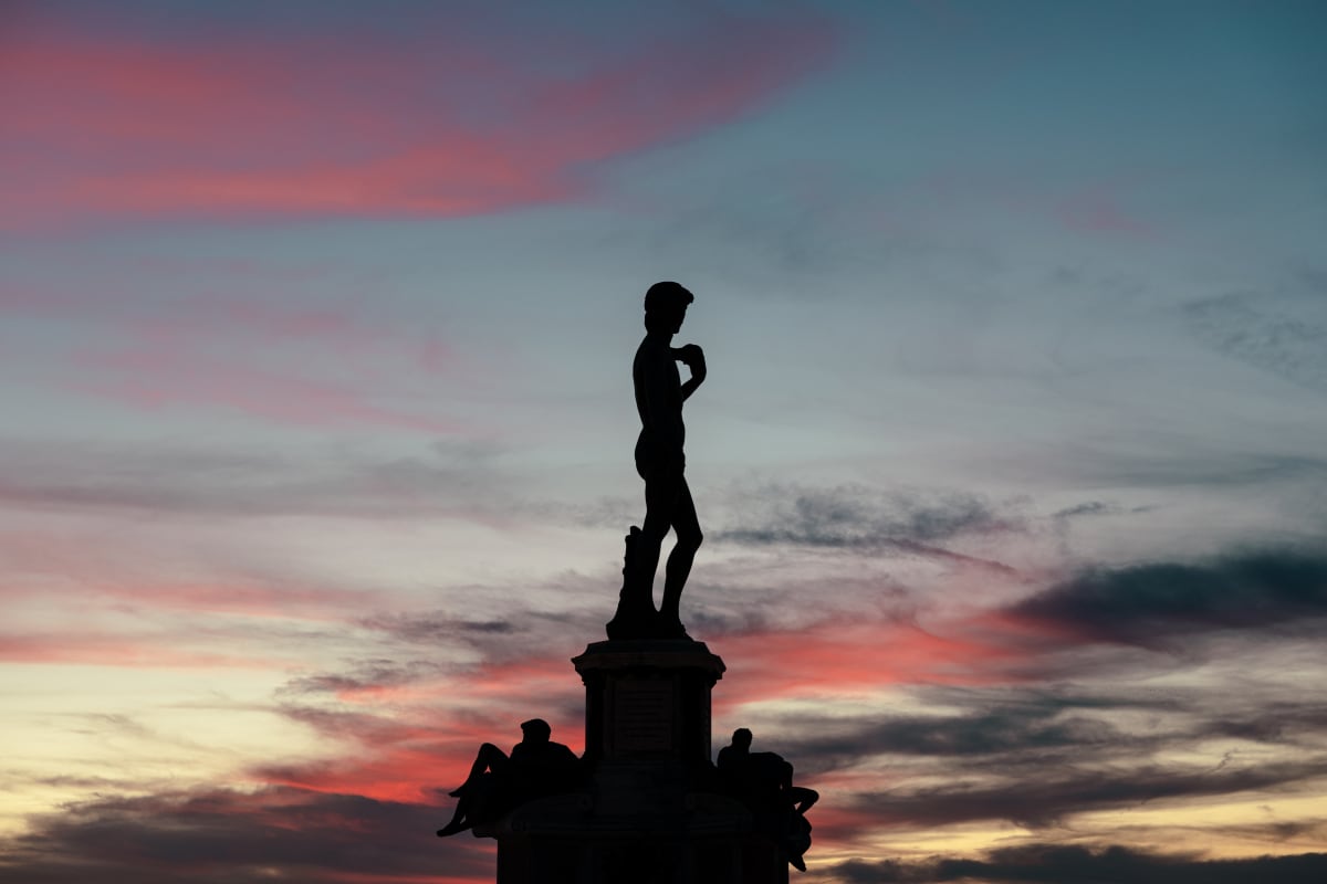 The silhouette of David against a pink and blue sunset