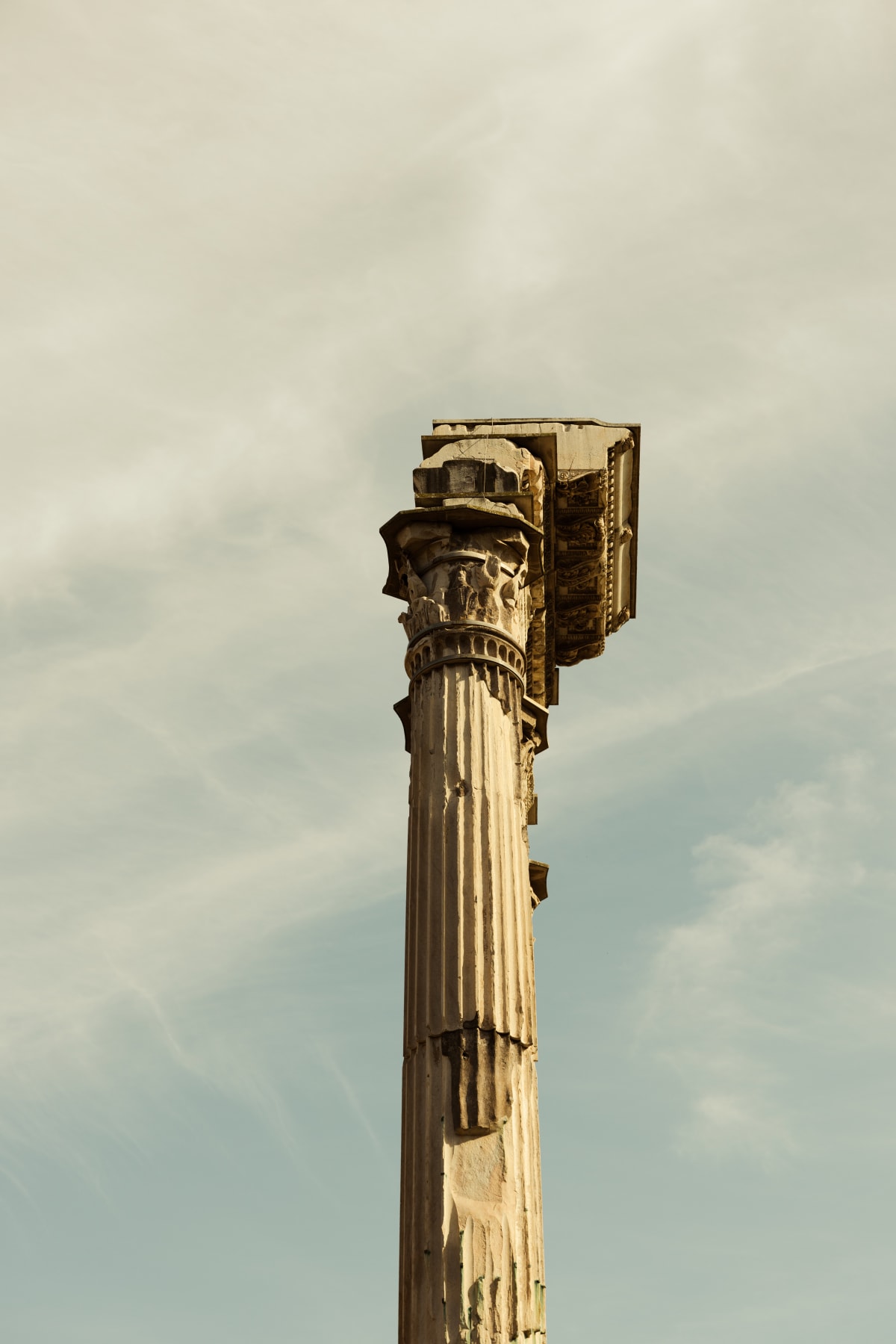 A weathered ancient column isolated against a pale sky