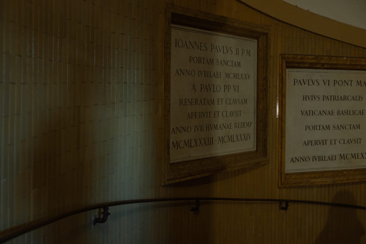 Latin inscriptions displayed along a dimly lit Vatican corridor