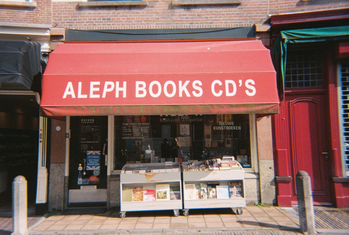 Books displayed beneath a red awning at an Amsterdam shop