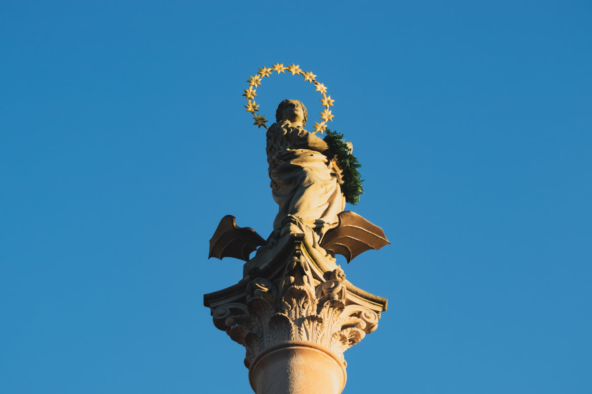 A sunlit Marian statue beneath a halo of golden stars