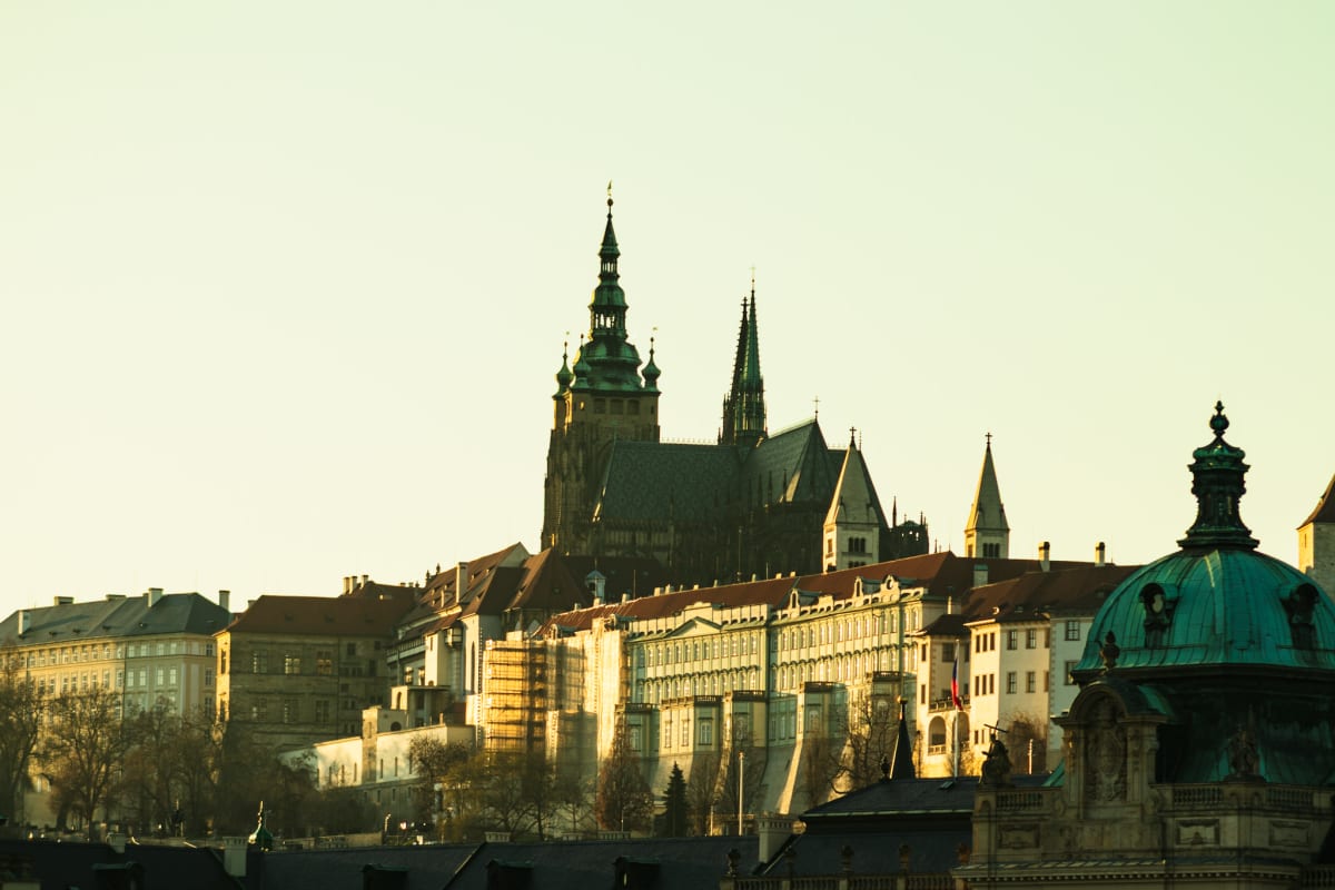 Prague Castle rising above sunlit historic rooftops