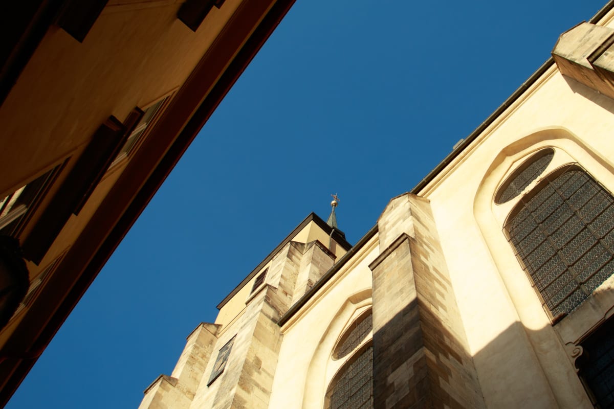 A pale church façade rising between buildings beneath a blue sky