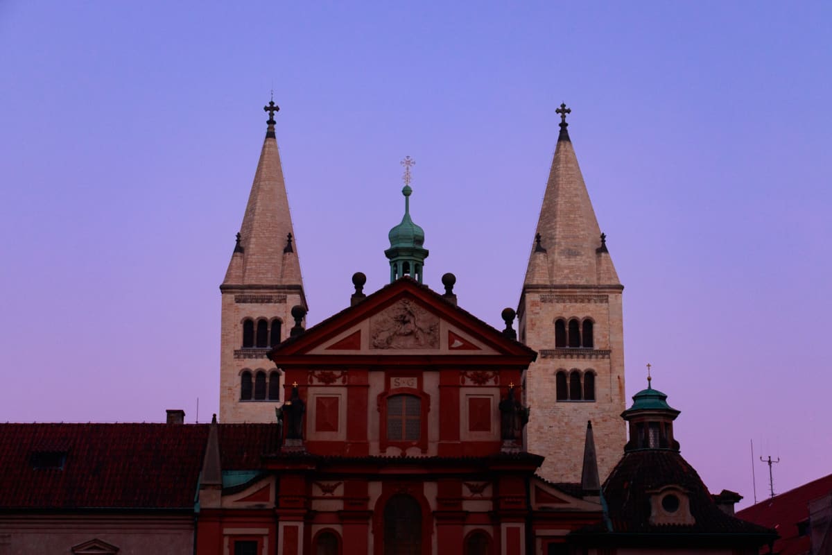 Twin church towers rising above a red Baroque façade at dusk