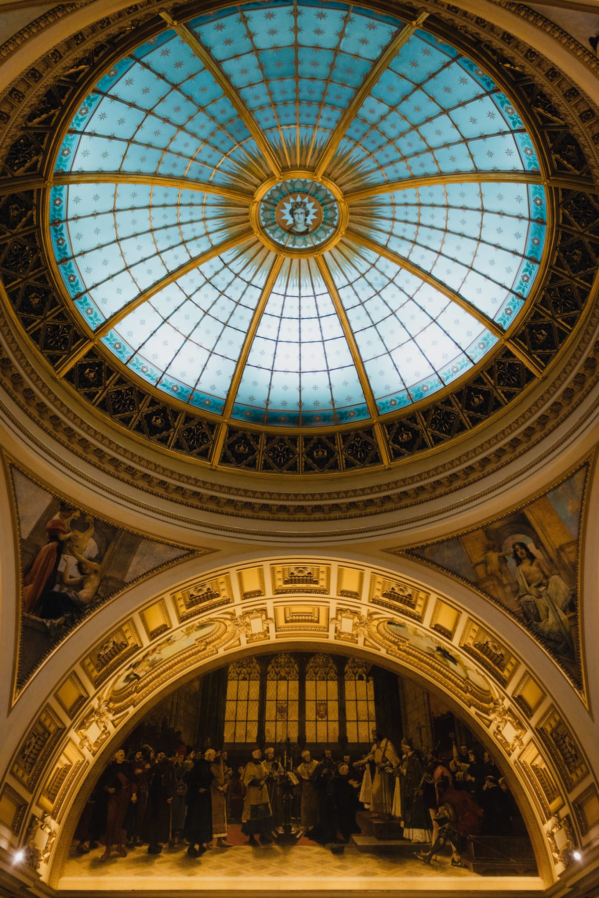 A turquoise glass dome above gilded arches and a historic mural