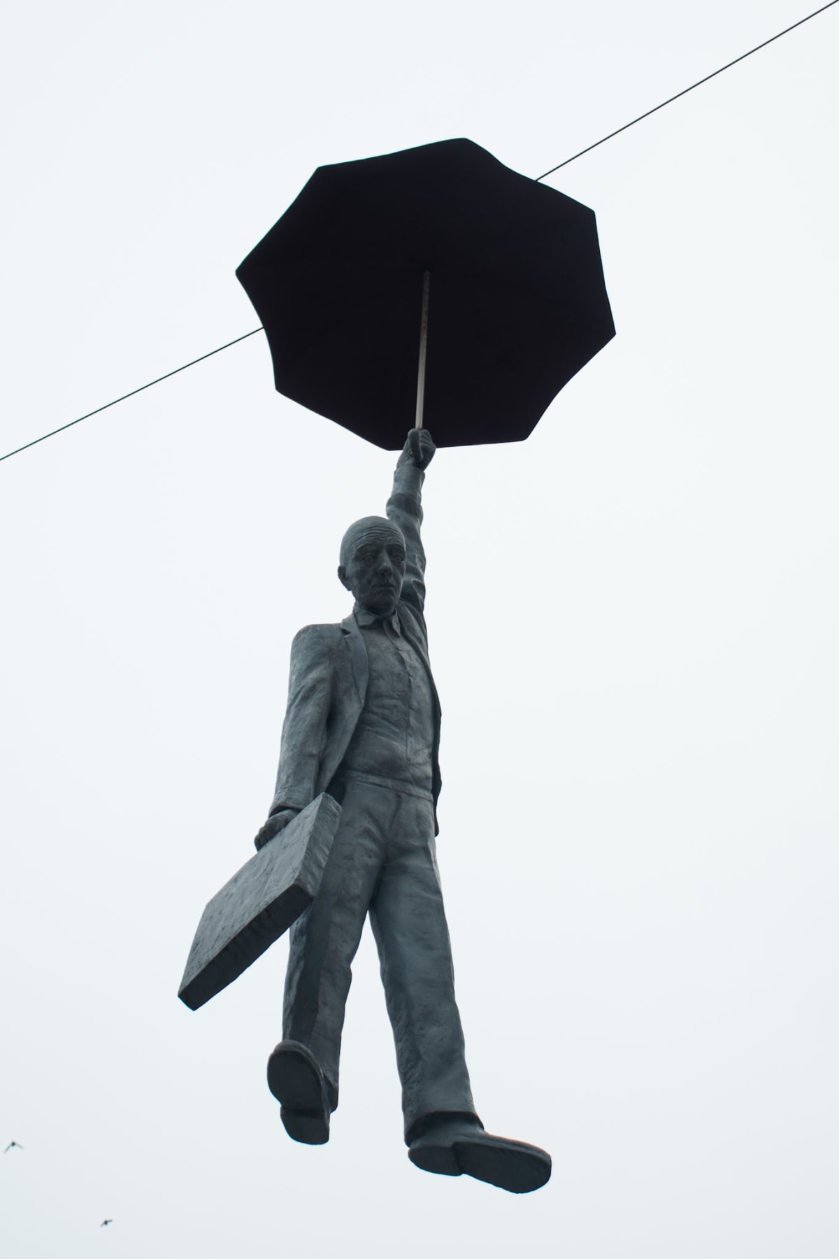 A suspended statue of a man holding an umbrella