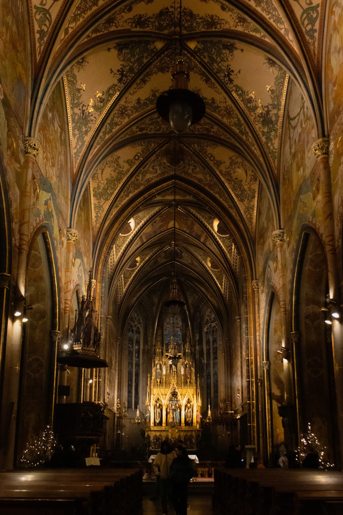 A warmly lit Gothic church nave with an ornate painted ceiling