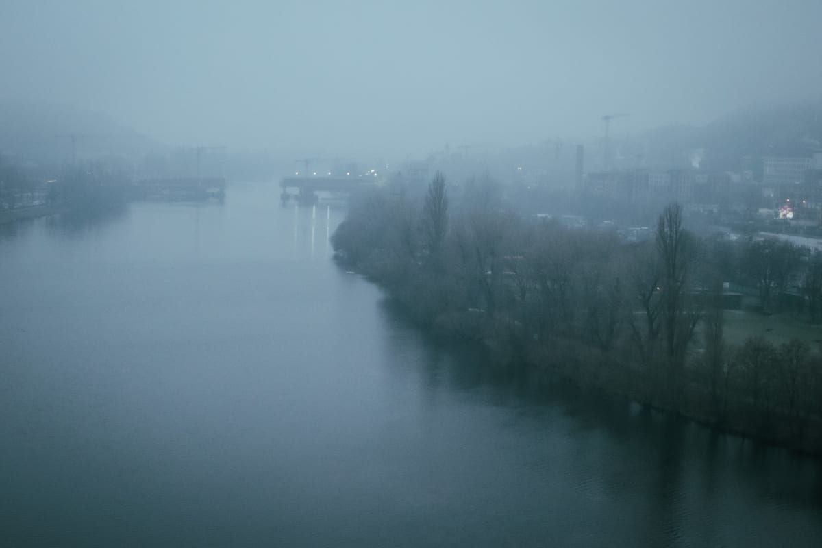 A wide river disappearing into dense blue-grey fog