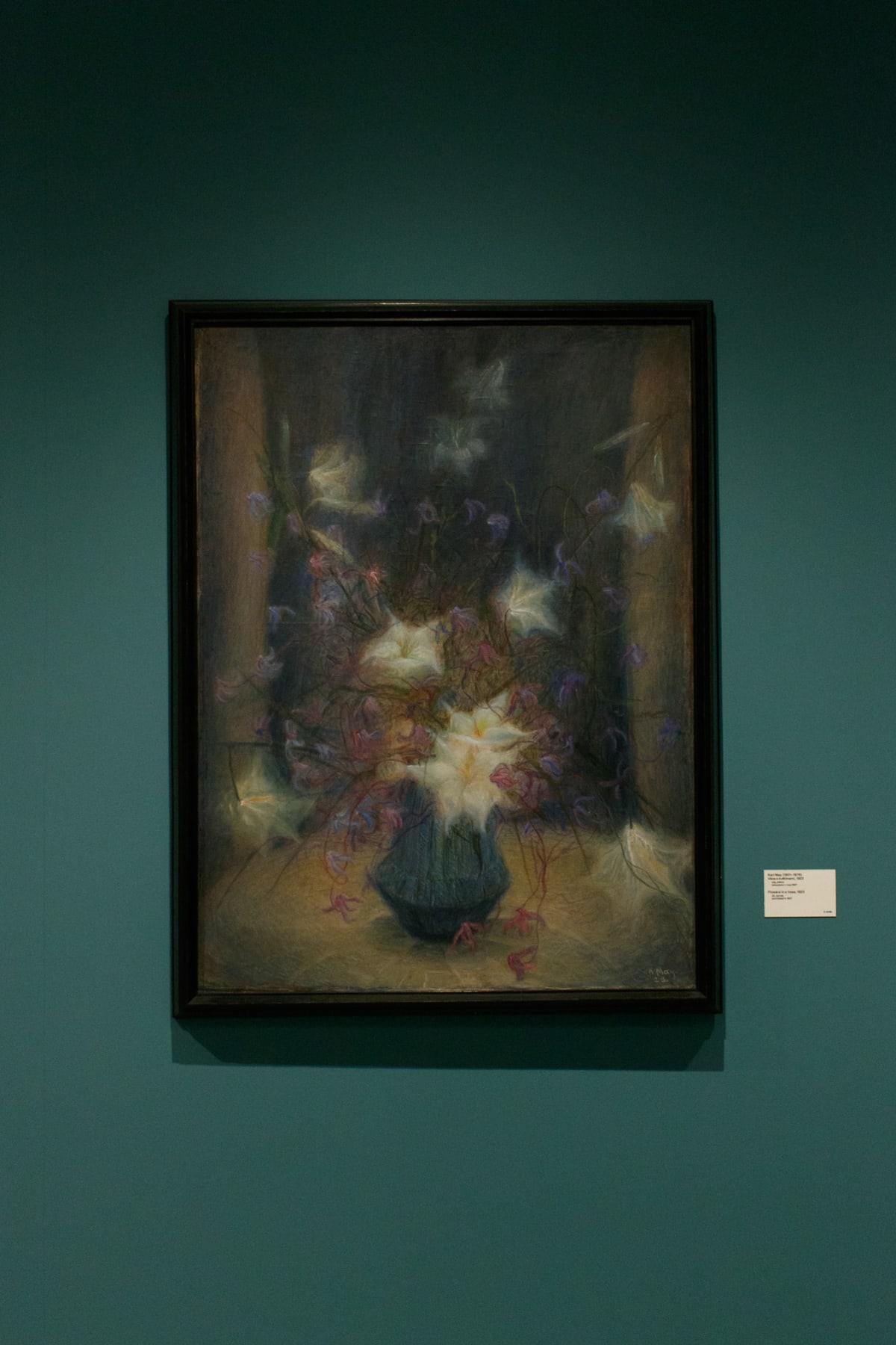 A luminous floral painting displayed on a deep green museum wall
