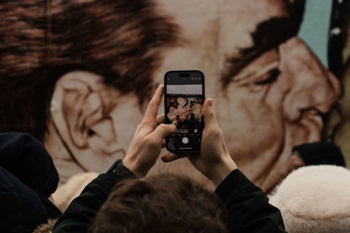 A visitor photographing a mural of a historic embrace