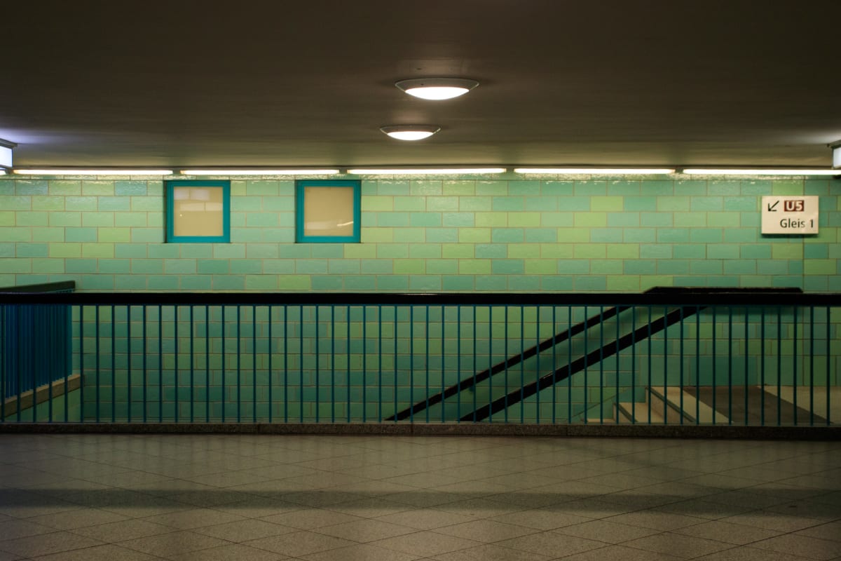 A quiet turquoise-tiled underground station landing