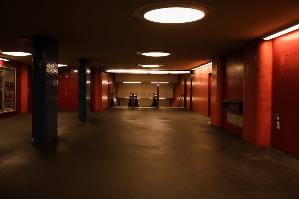 An empty red underground concourse beneath circular lights