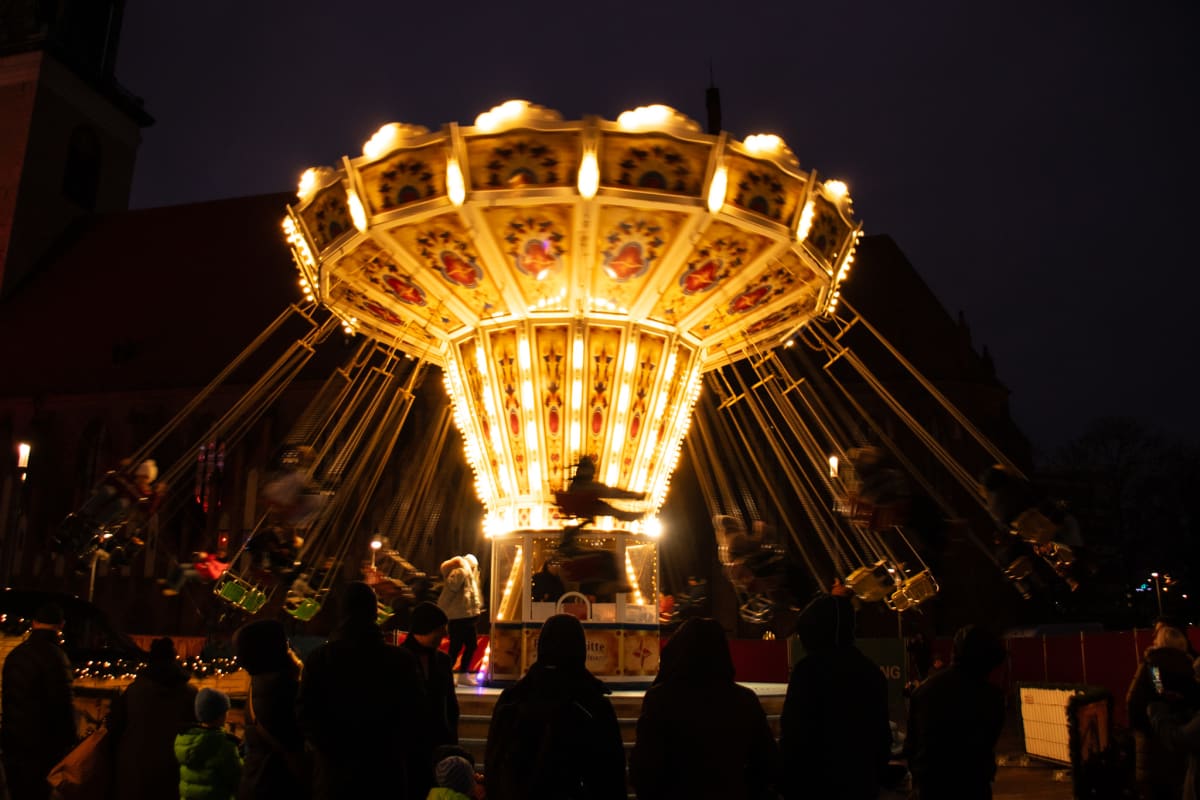 A brightly illuminated swing carousel turning at night