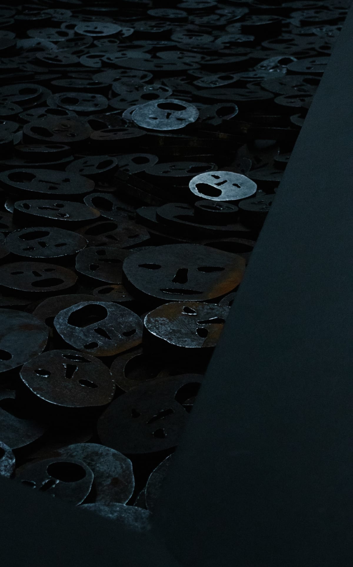 Dark metal faces scattered across a memorial installation