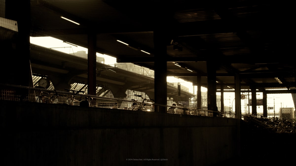 Bicycles and commuters silhouetted inside a shadowed transport structure