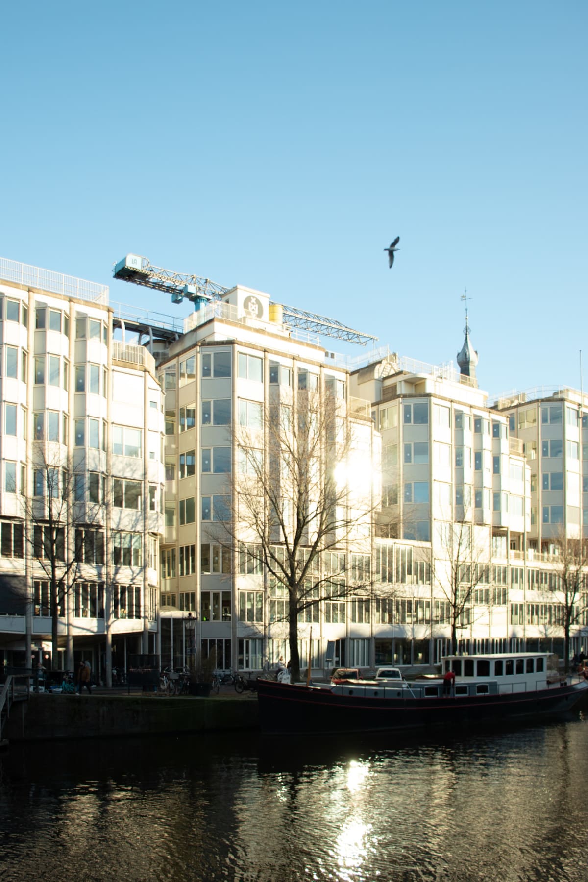 A canal boat and modern waterfront buildings reflecting afternoon light