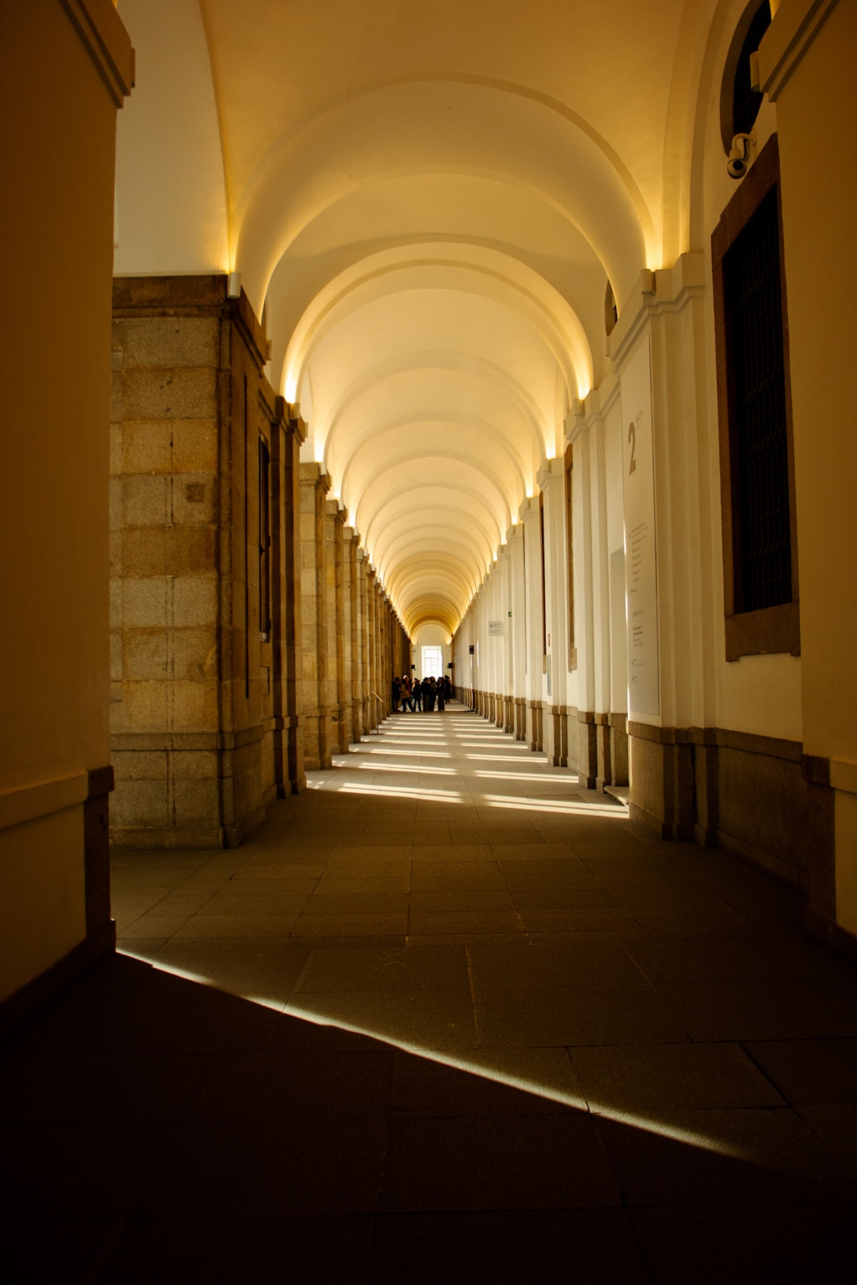 Warm light repeating through a long vaulted corridor