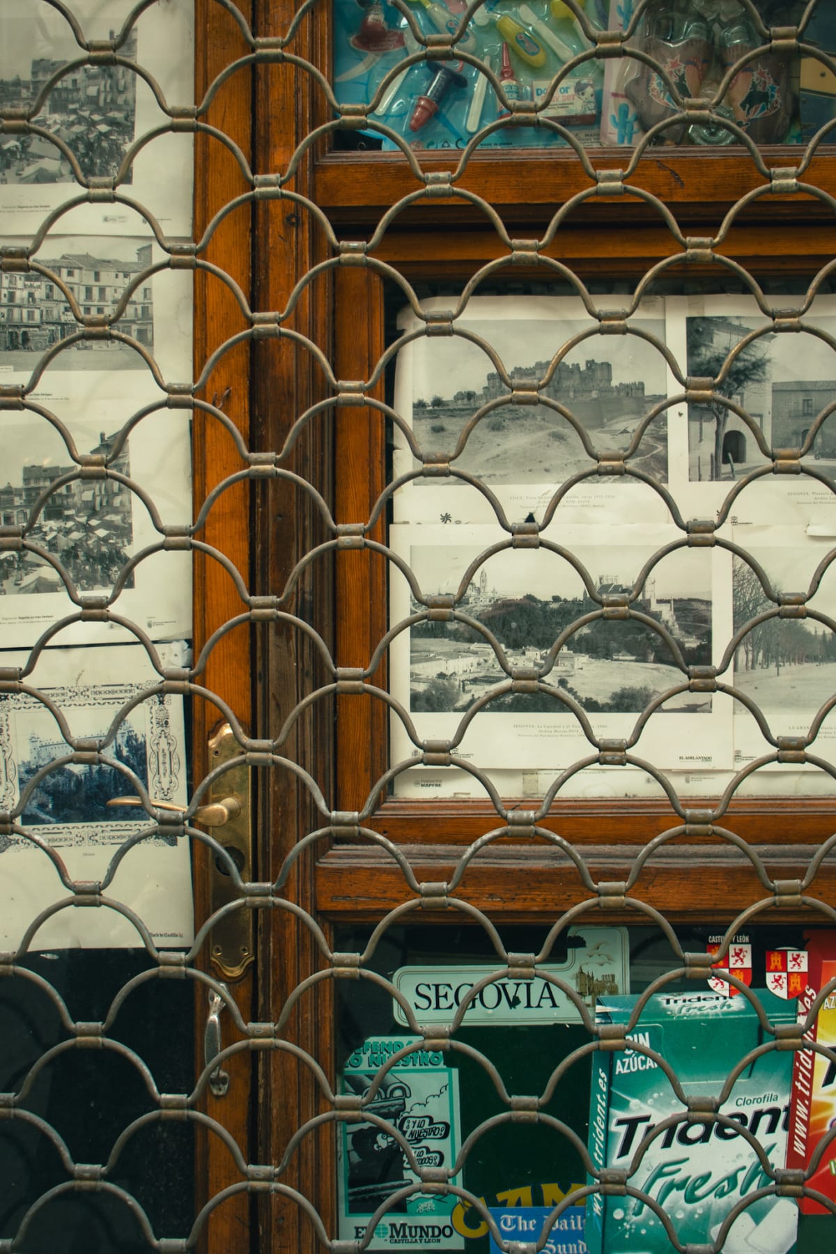 Vintage photographs displayed behind the metal grille of a Segovia shop