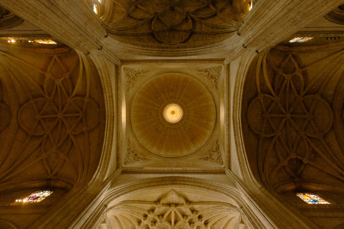 Symmetrical stone vaults and a circular skylight inside a cathedral