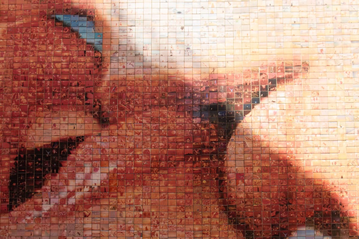 A sunlit mosaic wall composed of hundreds of small photographs