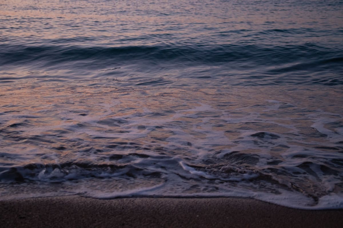 Small evening waves washing across a sandy shore