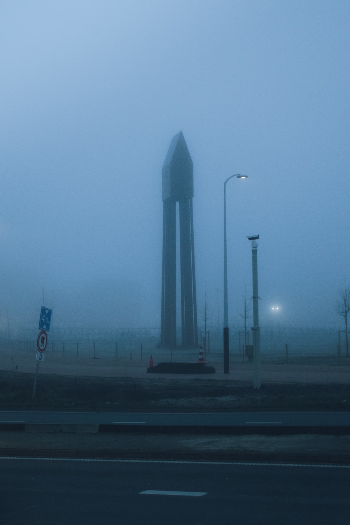 A tall geometric monument fading into dense blue fog