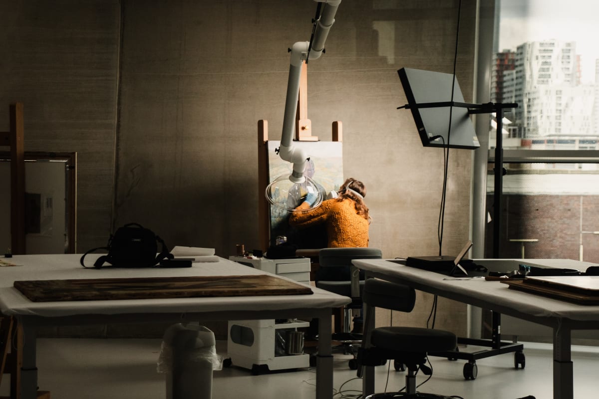A conservator working beneath an articulated lamp in a bright studio