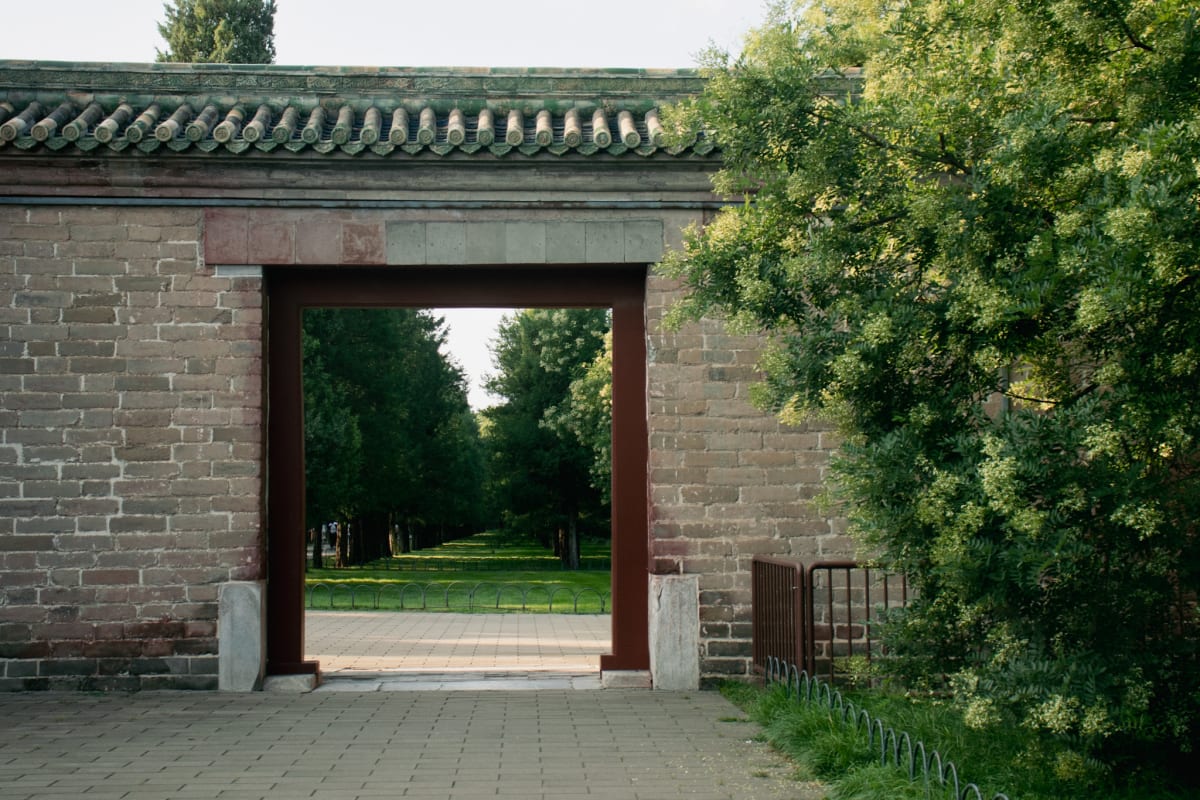 A traditional brick gateway opening onto a tree-lined path