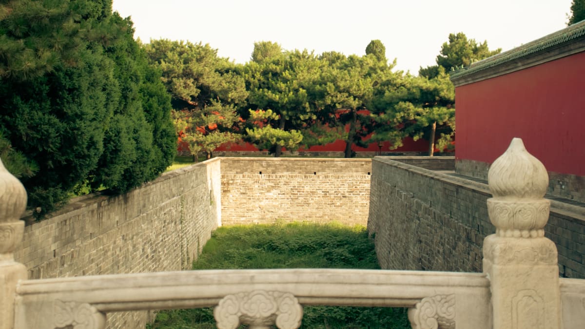 Stone balustrades and red palace walls surrounded by green trees
