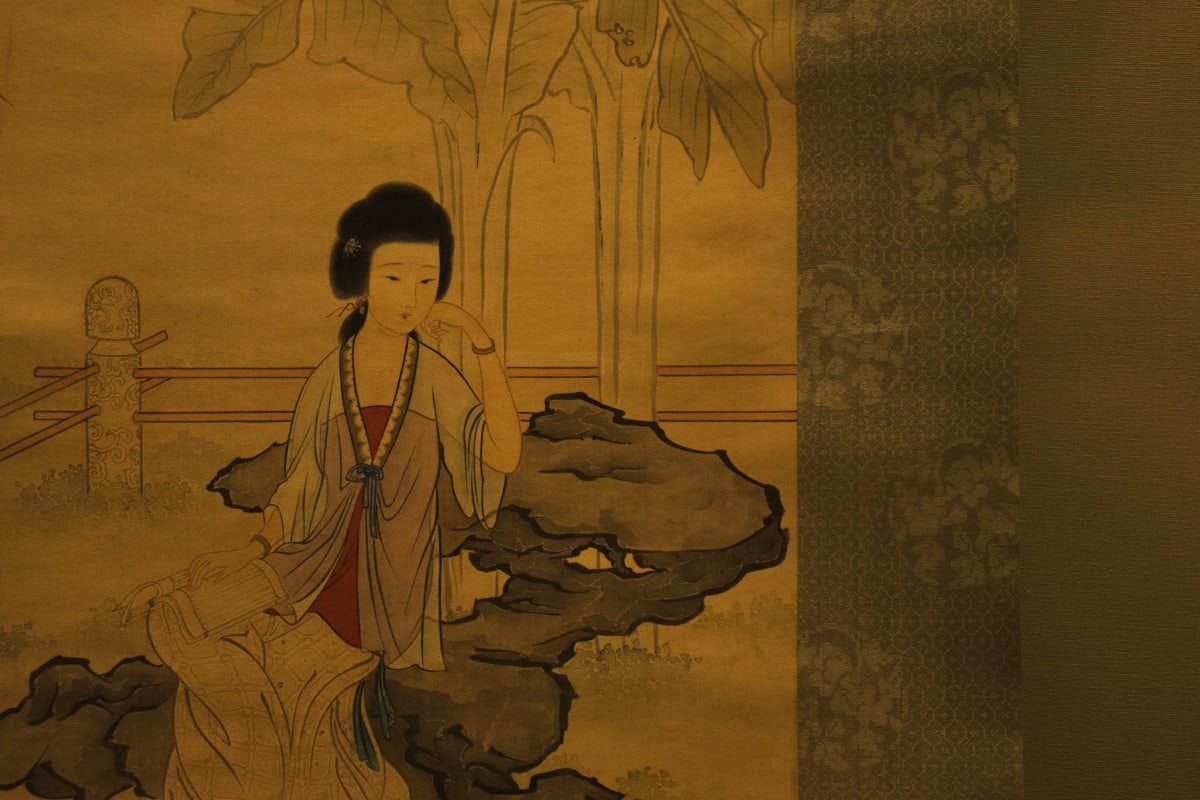 A classical Chinese painting of a seated woman beside garden rocks