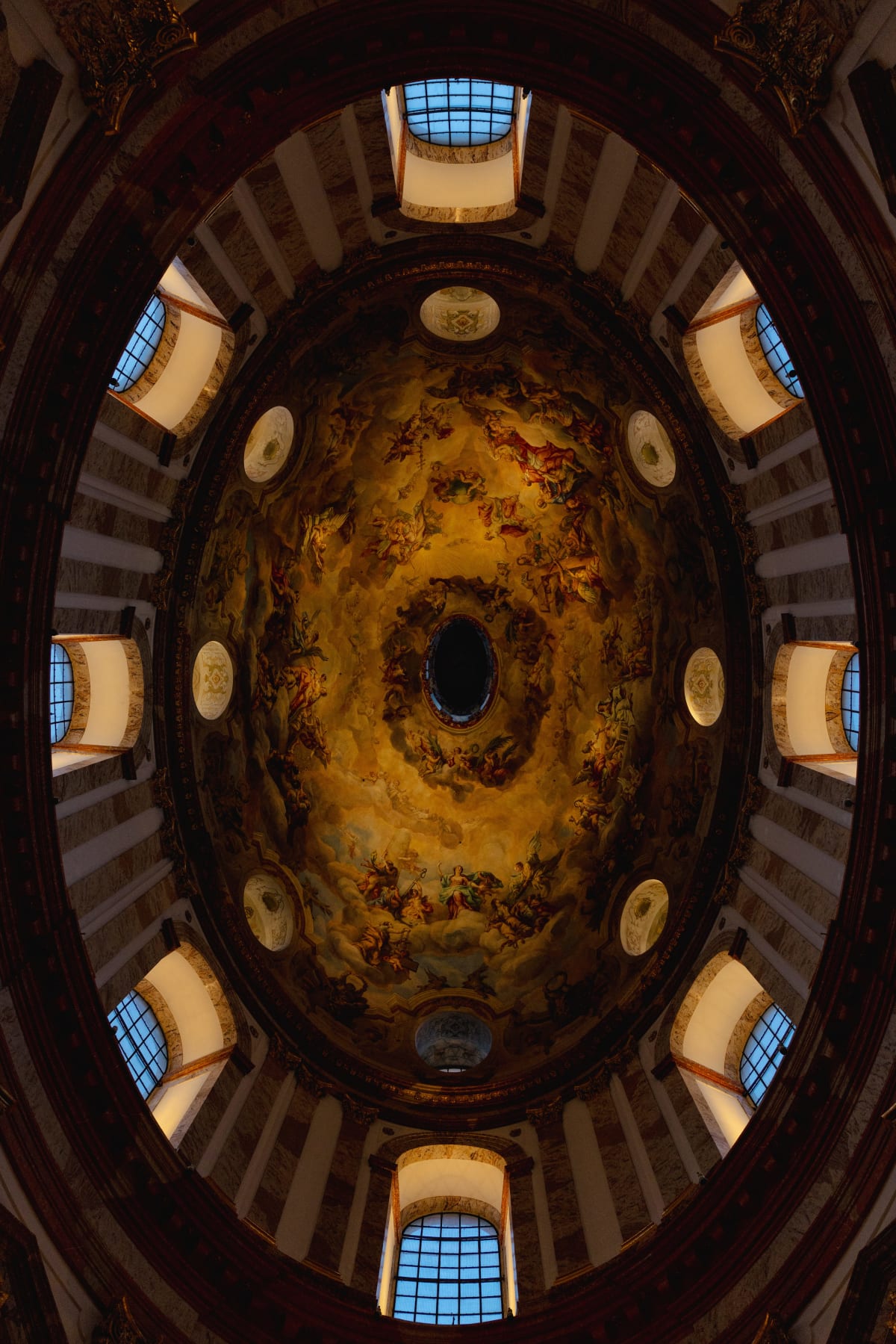 A richly painted oval ceiling surrounded by arched windows