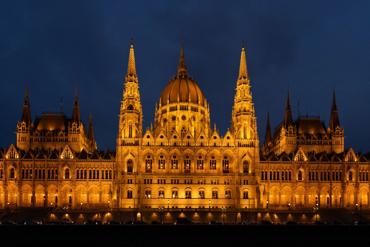The Hungarian Parliament illuminated beside the Danube at blue hour