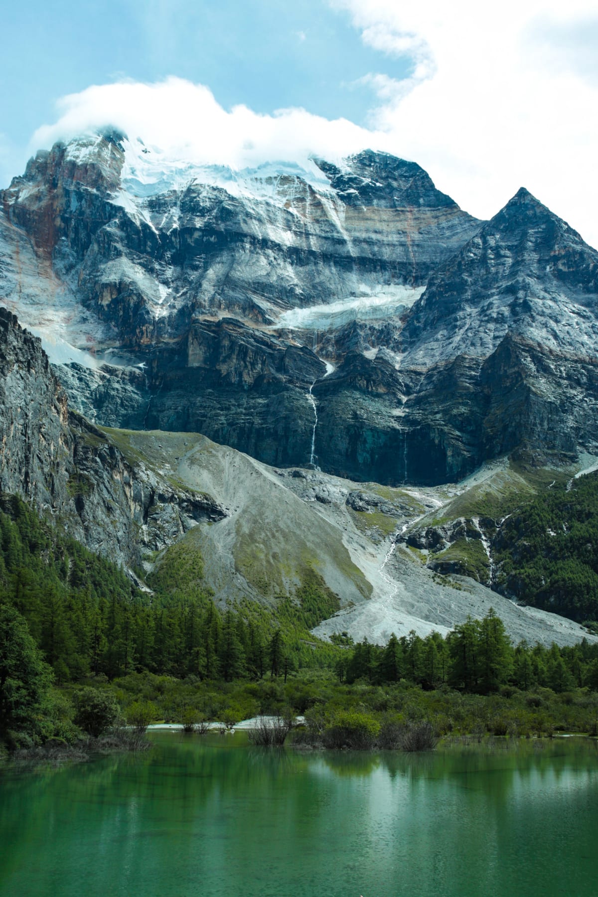 A snow-capped mountain rising above an emerald alpine lake