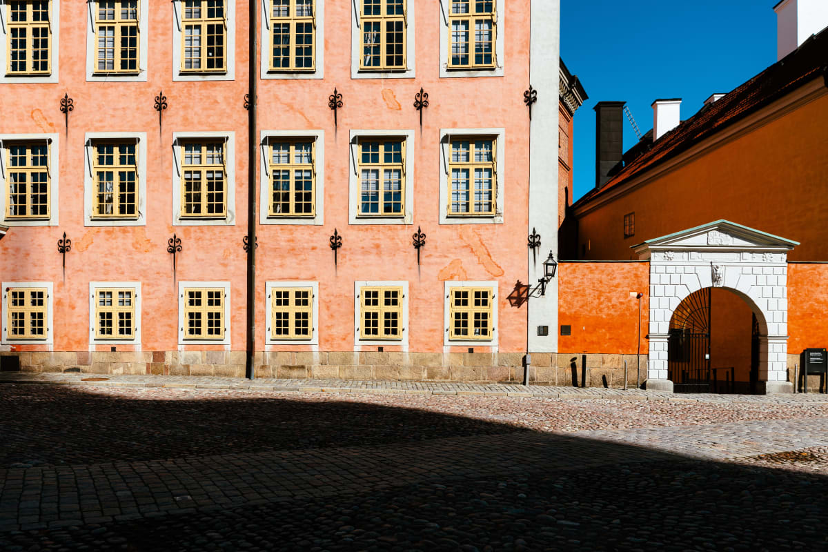 A vivid orange historic façade crossed by afternoon shadows