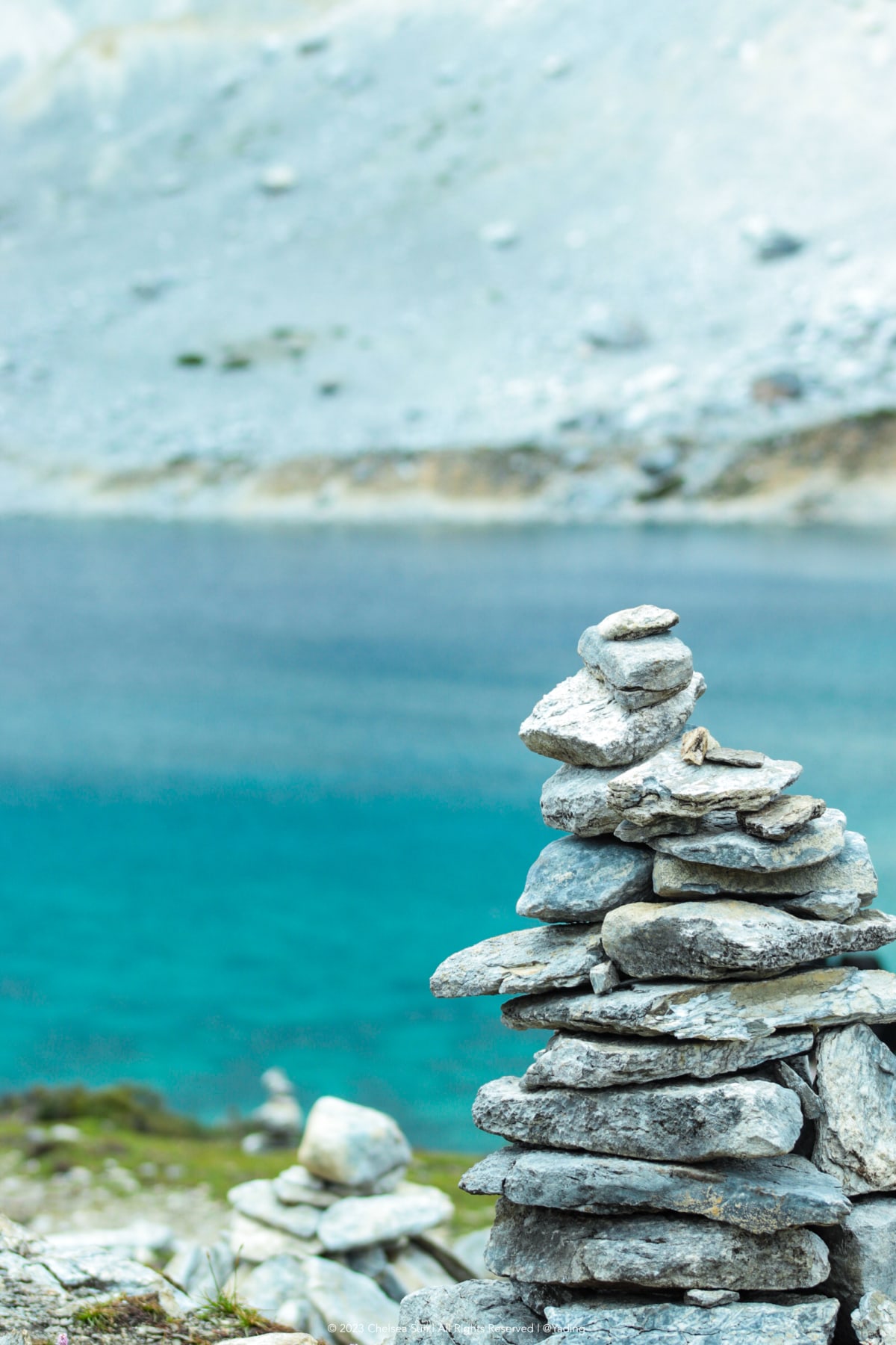 A stone cairn beside a turquoise alpine lake