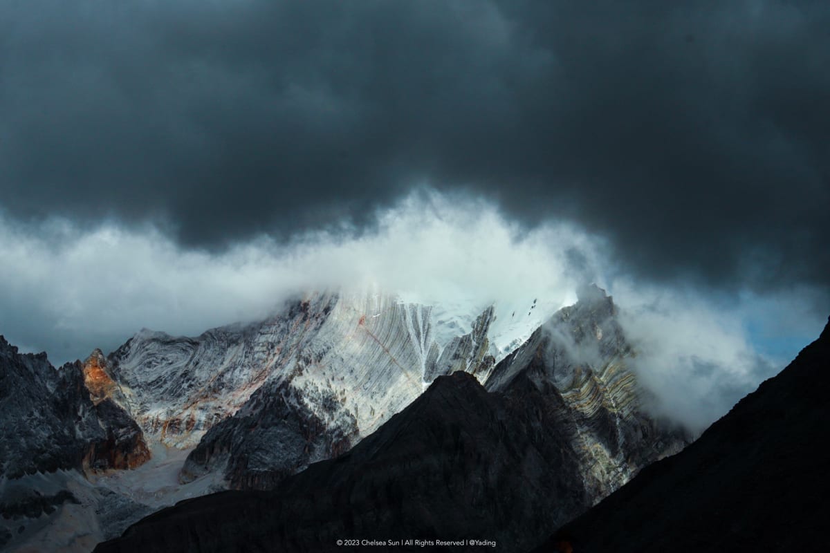 A snow-covered mountain beneath dark storm clouds