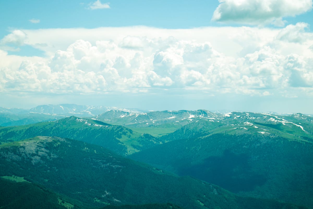 Layered green mountain ridges beneath a long band of bright clouds
