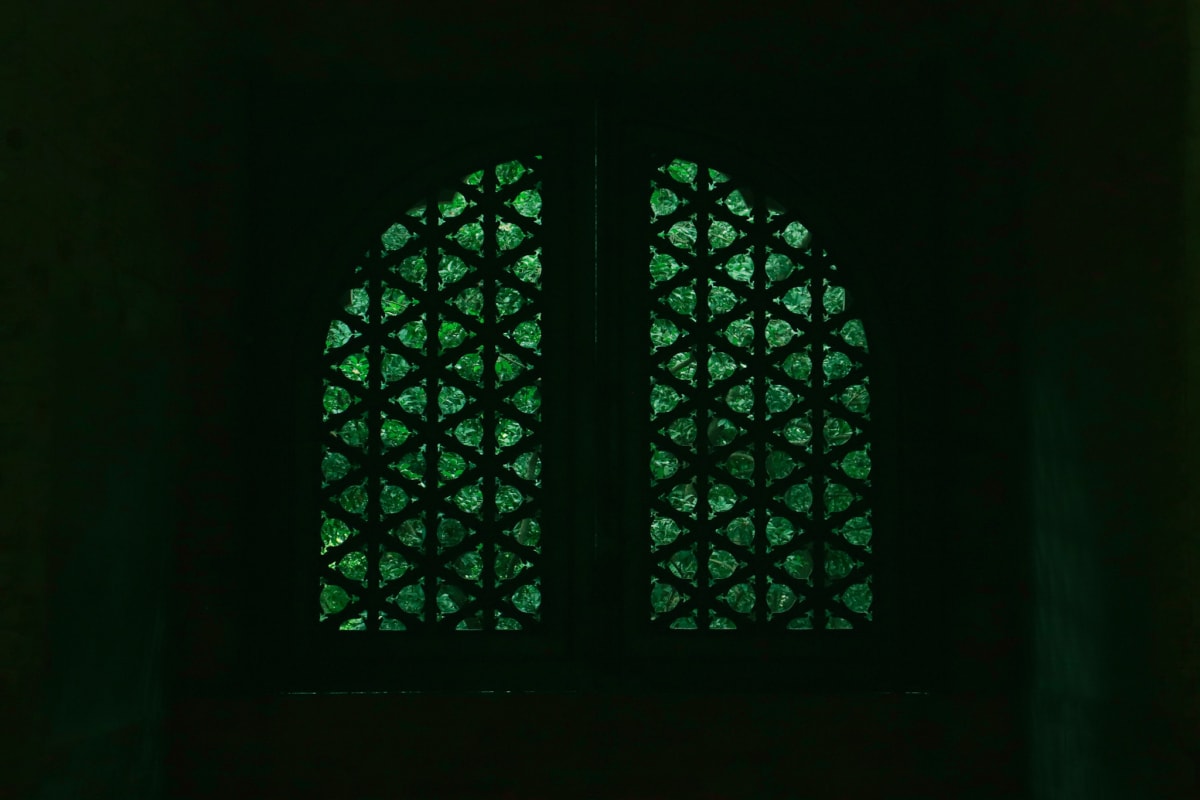 Green light filtering through a patterned arched window