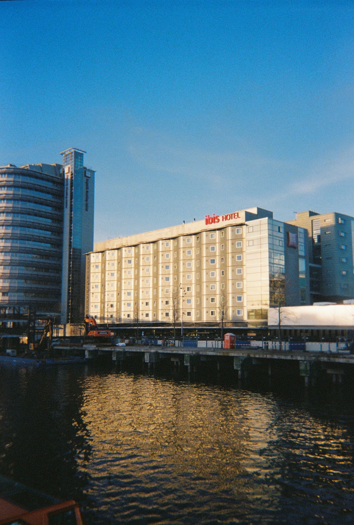 Waterfront buildings reflecting warm sunlight beneath a clear blue sky