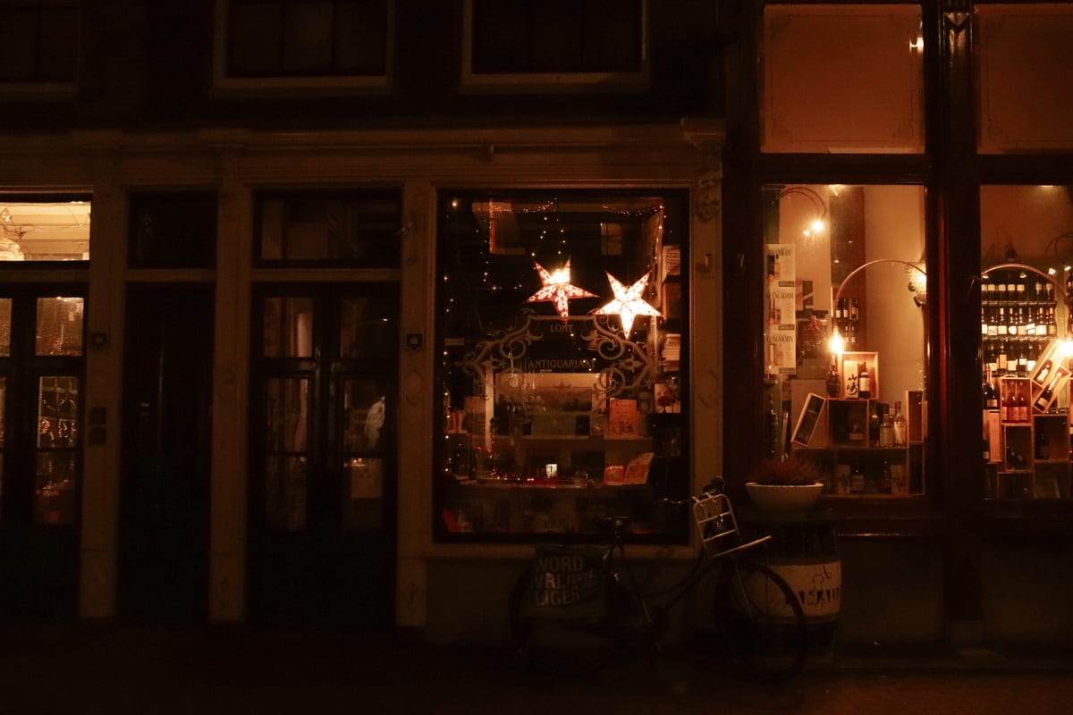 Warm shop windows and a bicycle glowing on a dark Amsterdam street