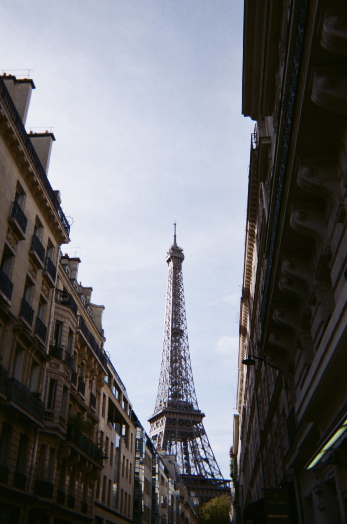 The Eiffel Tower framed between shadowed Parisian buildings