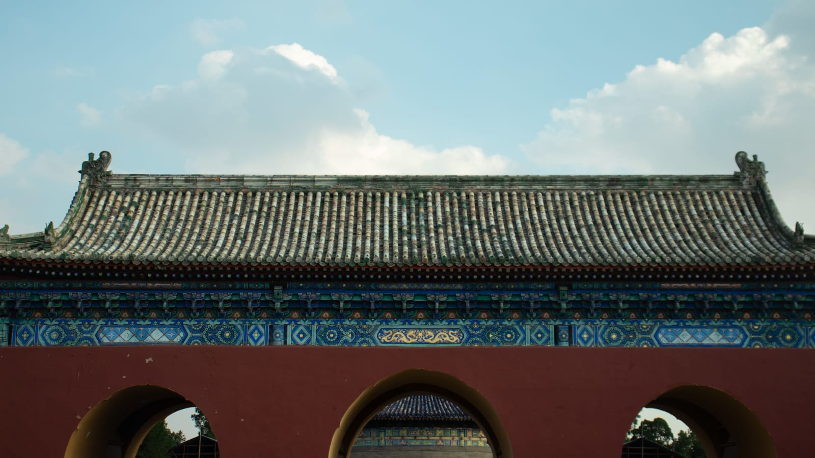 A traditional red gate and tiled roof beneath a bright blue sky