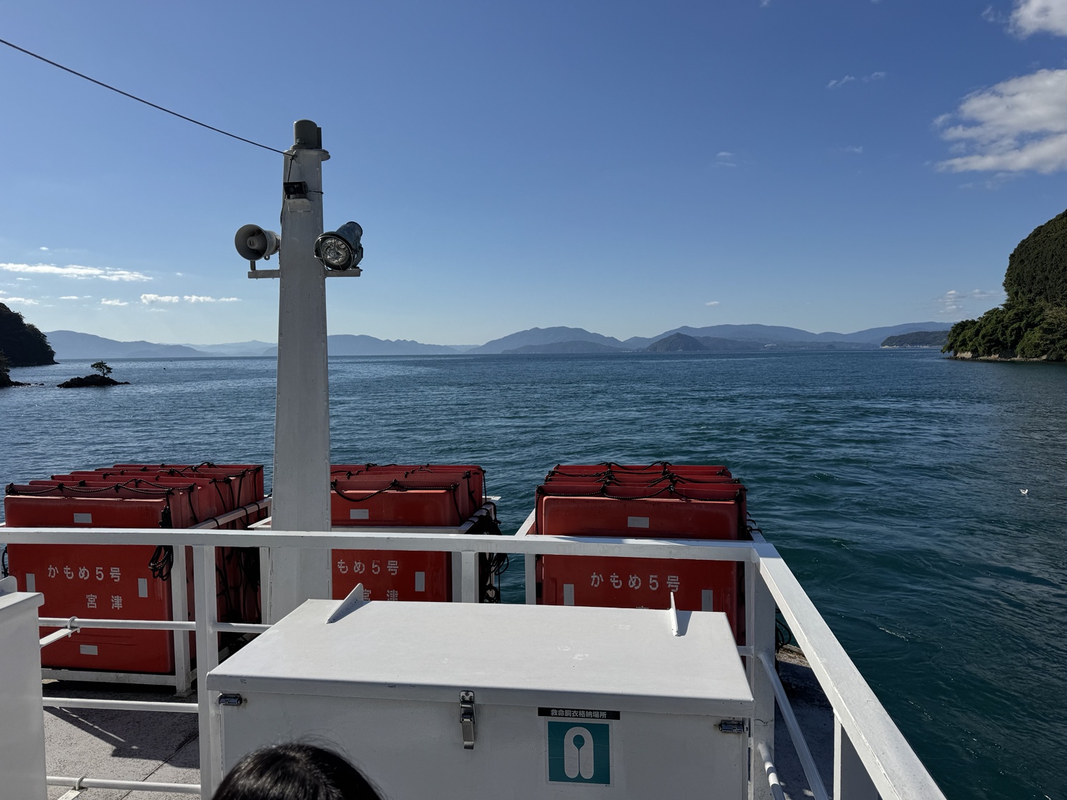 Rows of red seats aboard the boat, with water and hills beyond